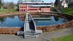 Ein kreisförmiges Klärbecken mit einer Brücke oben drüber.