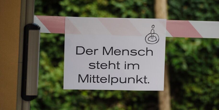 Ansicht eines Schildes mit Aufschrift "Der Mensch steht im Mittelpunt"